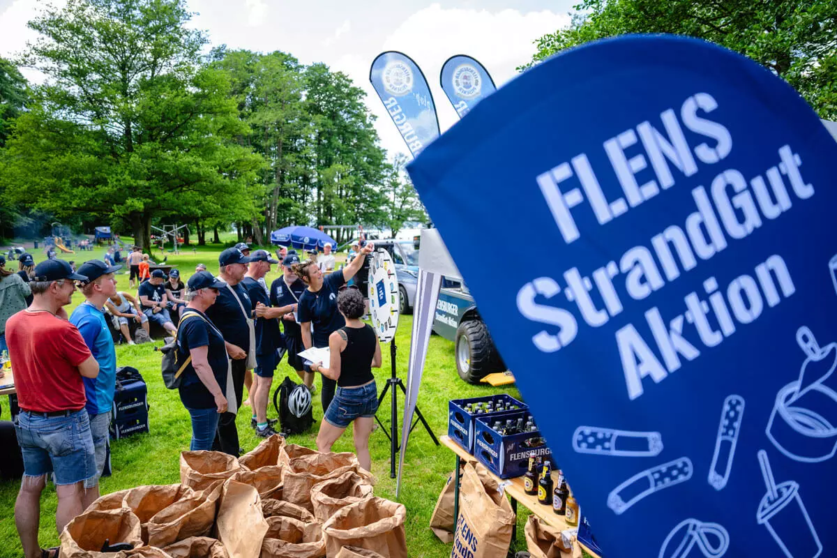 Menschenmenge, die sich nach der Strandreinigungsaktion bei einem Glücksrad vergnügt.