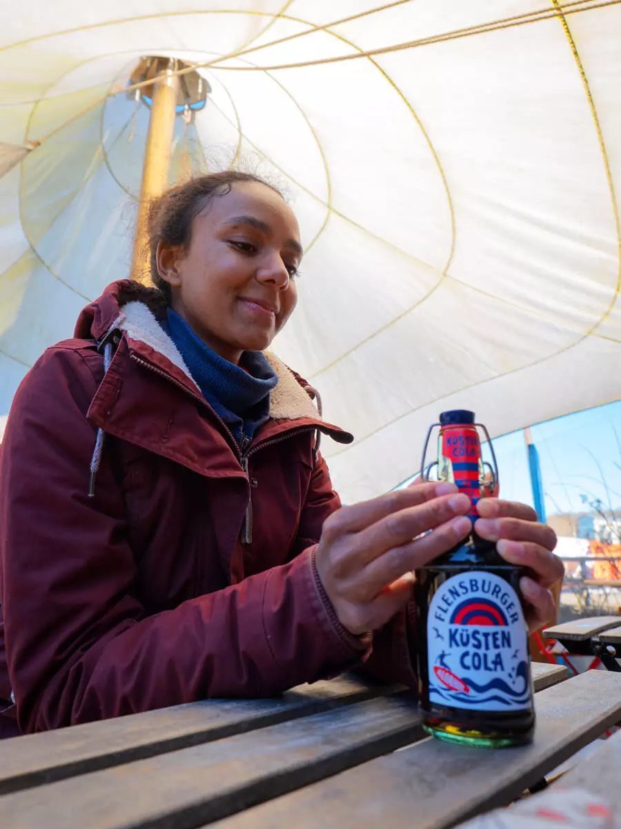 Eine Frau freut sich darauf ihre Küstencola aufzuplopen.