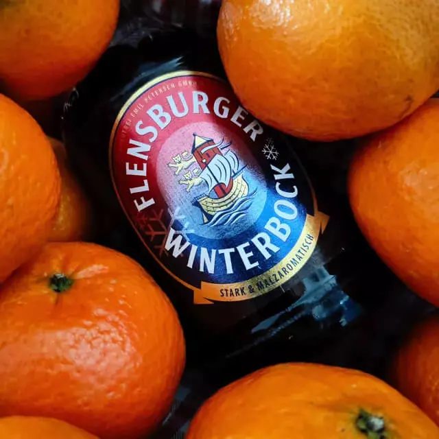 Eine Flasche Flensburger Winterbock liegt zwischen vielen Orangen.