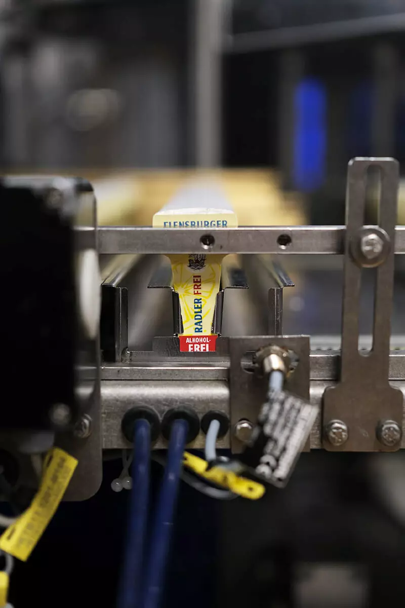 Die Halsetiketten vom Flensburger Radler Frei liegen in der Schiene der Etikettiermaschine.