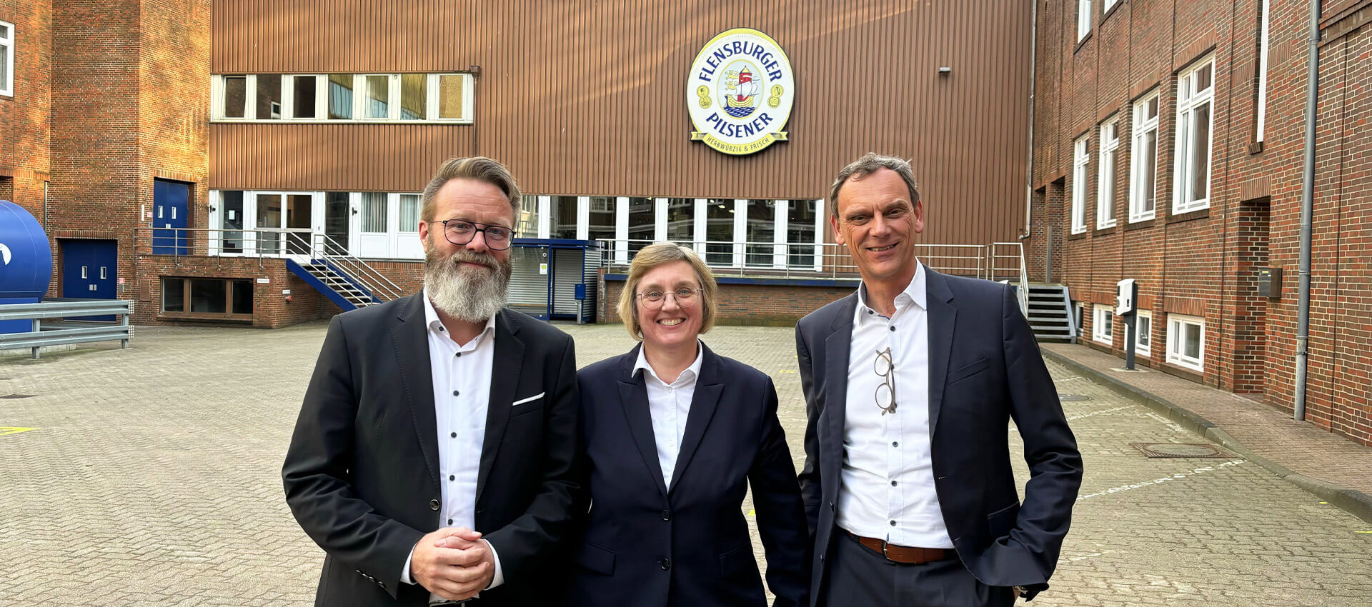 Claus Ruhe Madsen, Sylke Moerke und Jörn Schumann im Innenhof der Flensburger Brauerei.